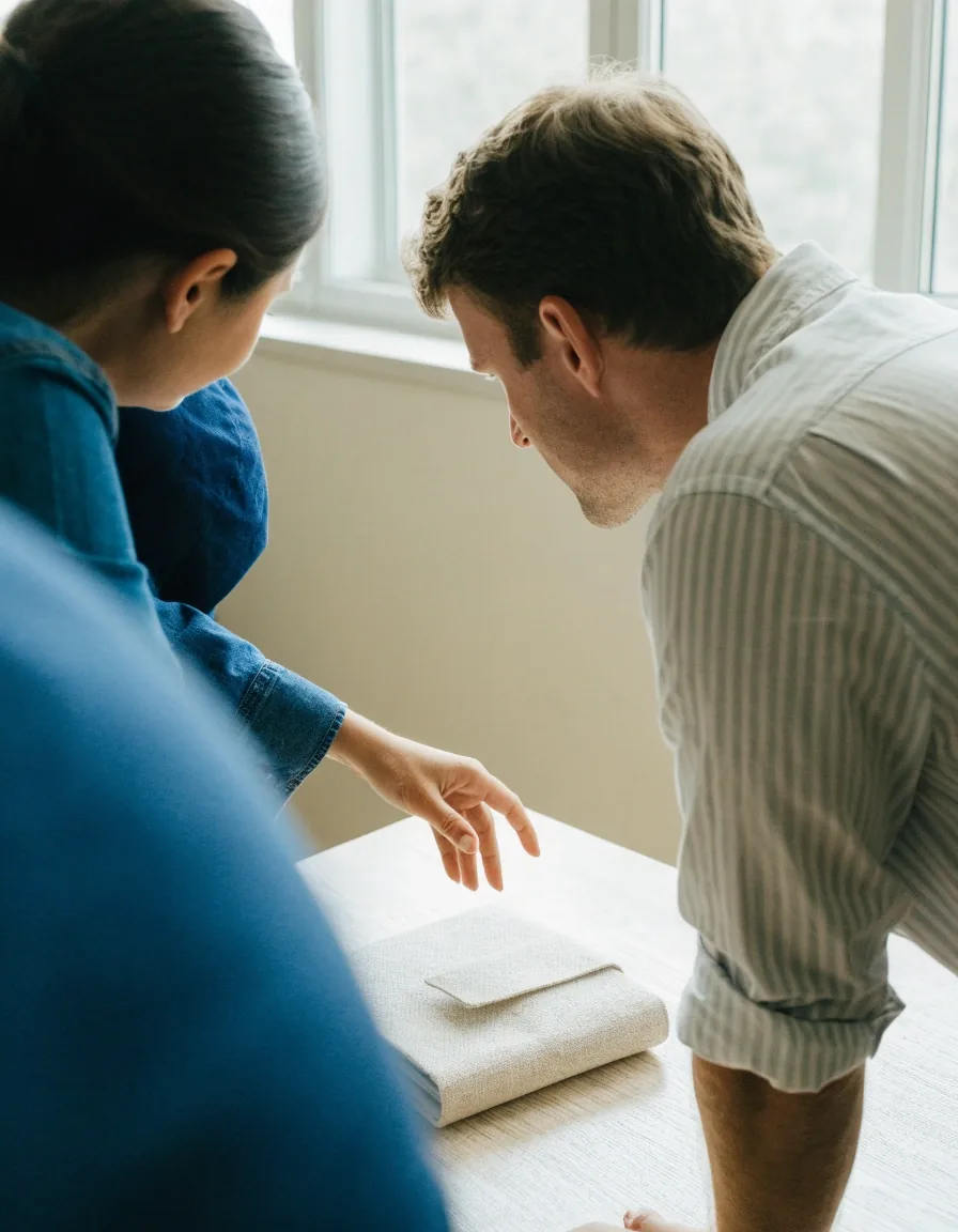 Two consultants mid-conversation across a light table in a service business office, seen from behind one shoulder